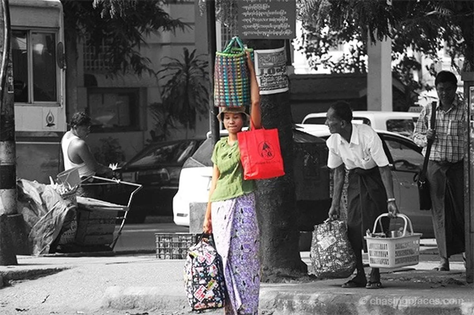 Three bags, two arms and one neck. This woman waits patiently in the humid heat of Yangon for a bus to arrive.